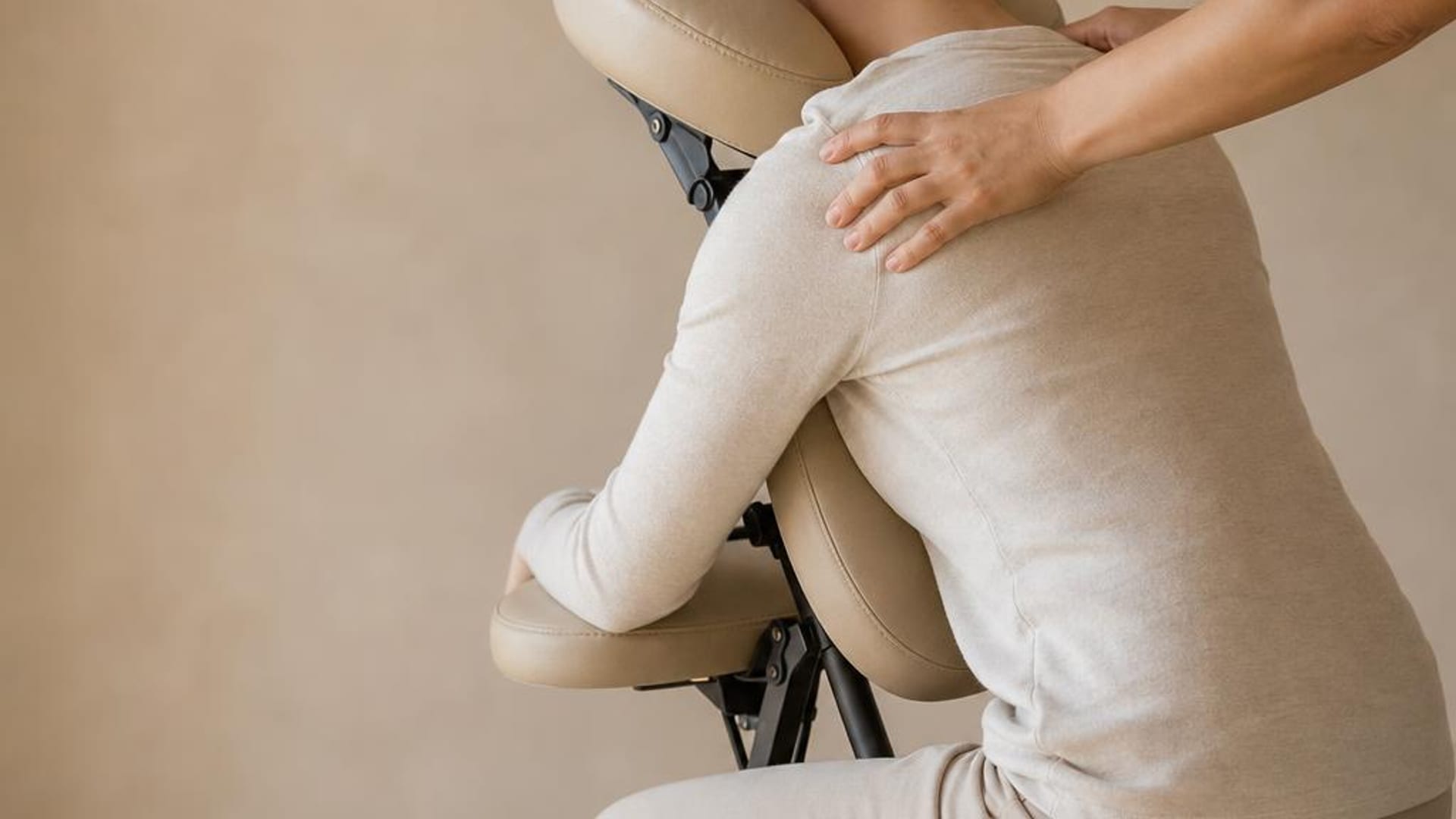 Therapist massaging the shoulders of a seated, fully clothed guest in a massage chair