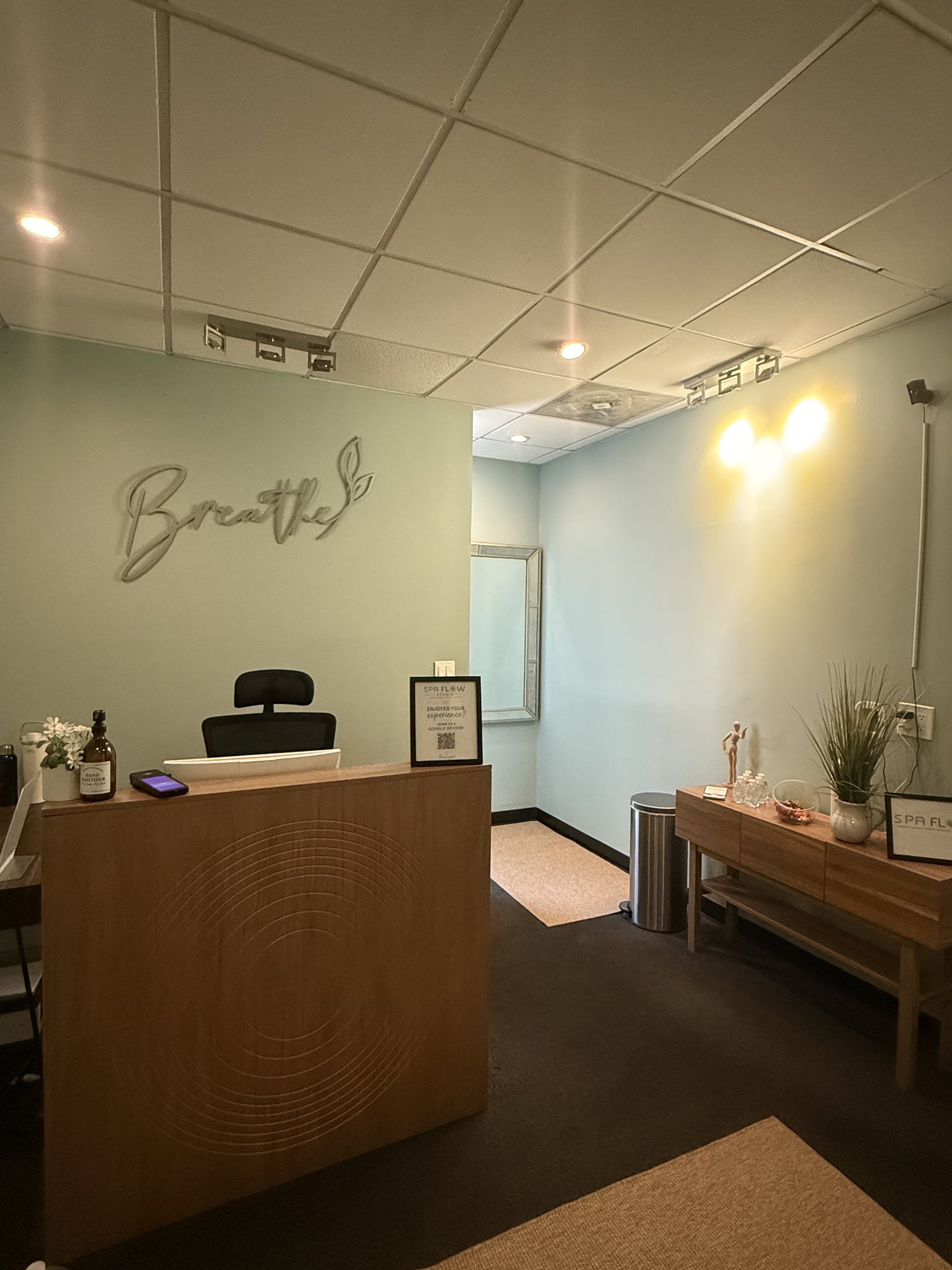 Spa Flow Studio reception desk beneath a "Breathe" wall sign